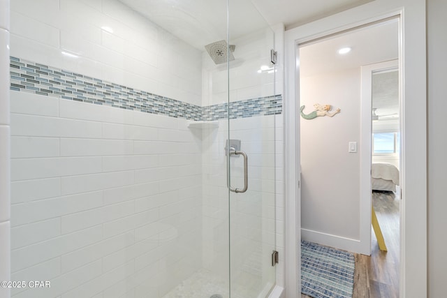 bathroom with ensuite bath, baseboards, wood finished floors, and a shower stall