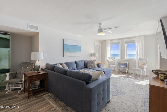 living room featuring a textured ceiling, wood finished floors, visible vents, and a ceiling fan