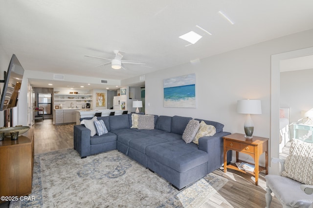 living area featuring ceiling fan, visible vents, and wood finished floors