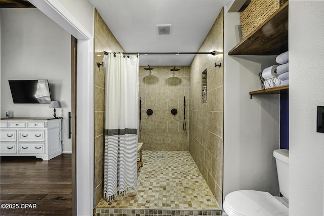 bathroom with toilet, a stall shower, visible vents, and wood finished floors