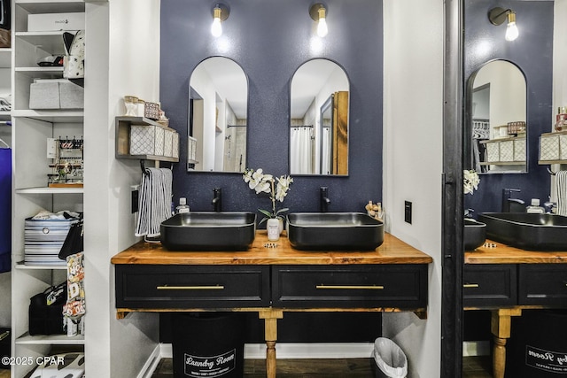 full bath featuring double vanity, baseboards, and a sink