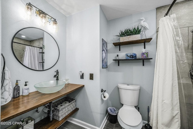 full bath featuring baseboards, tiled shower, a sink, and toilet