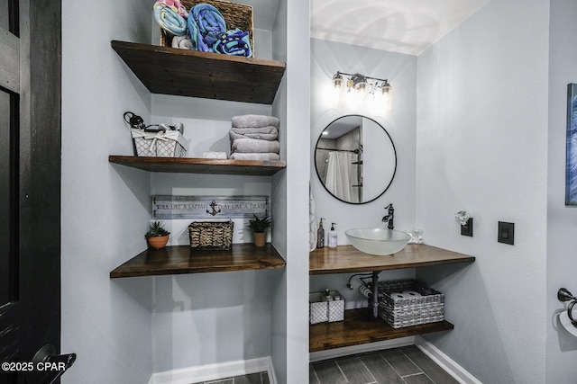 bathroom with baseboards, wood finished floors, and vanity