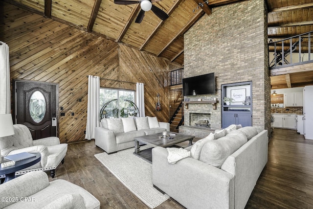 living room featuring wooden walls, dark wood-type flooring, a fireplace, wood ceiling, and beam ceiling