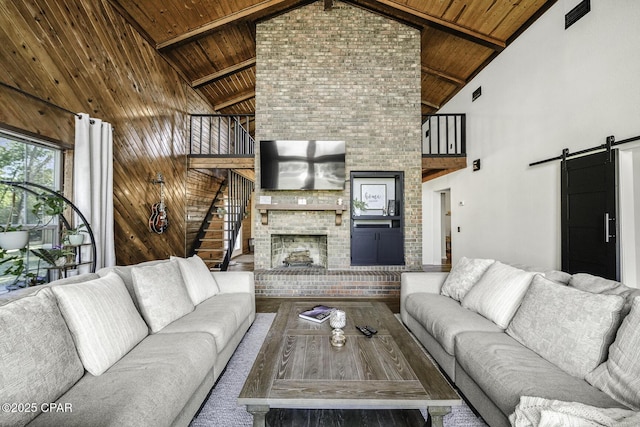 living room featuring a brick fireplace, wooden ceiling, beam ceiling, and a barn door