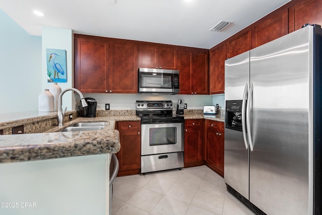kitchen with visible vents, a sink, appliances with stainless steel finishes, light stone countertops, and dark brown cabinets
