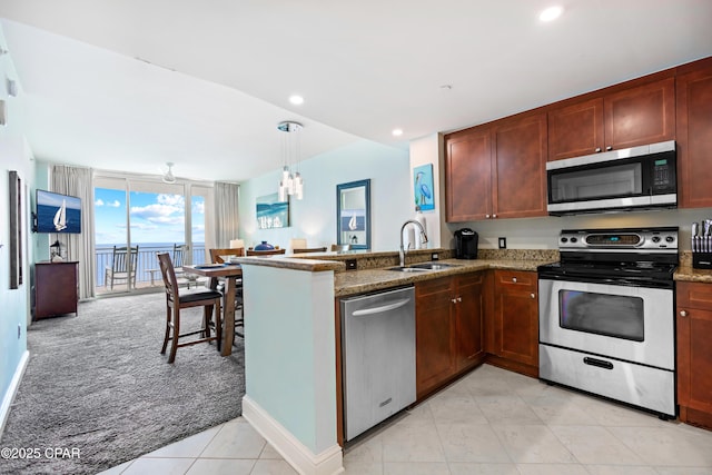 kitchen featuring light carpet, a sink, stone countertops, stainless steel appliances, and a peninsula