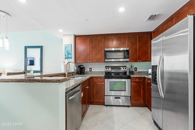 kitchen with light stone counters, visible vents, a peninsula, a sink, and appliances with stainless steel finishes