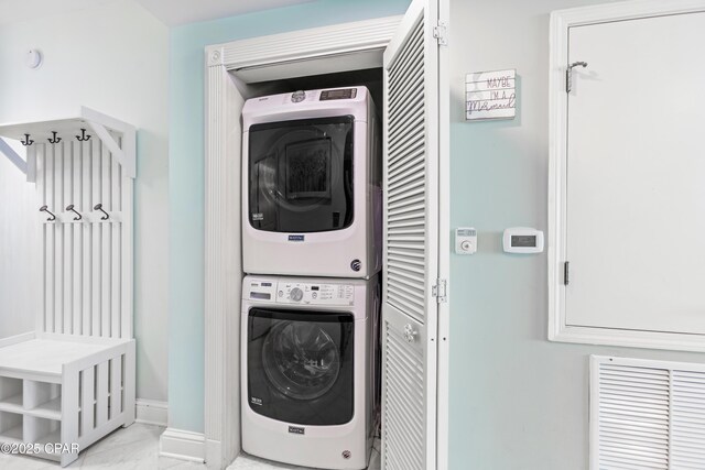laundry area featuring baseboards, visible vents, laundry area, stacked washer / dryer, and marble finish floor