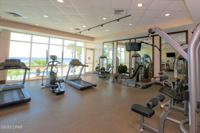 workout area with rail lighting, visible vents, and a drop ceiling