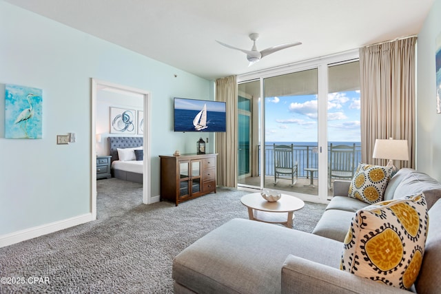 living room with ceiling fan, baseboards, a wall of windows, and carpet