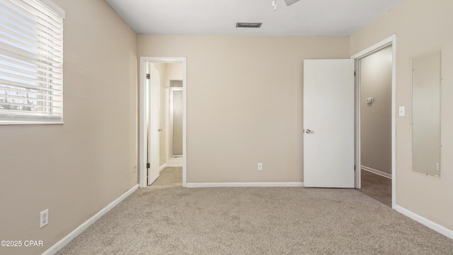 unfurnished bedroom with ensuite bath, carpet, visible vents, and baseboards