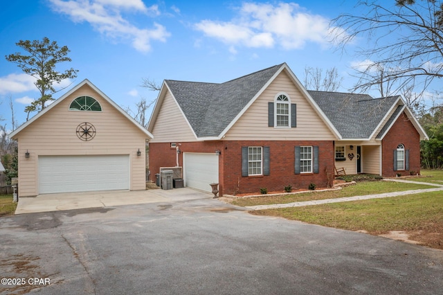 traditional home with a garage, a shingled roof, a front yard, and brick siding