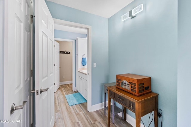 hallway featuring light wood-type flooring and baseboards