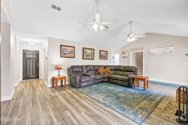 living room featuring baseboards, visible vents, vaulted ceiling, and light wood finished floors