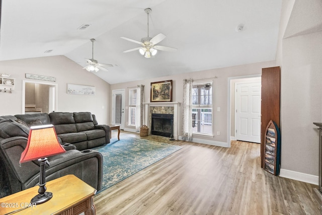 living room with vaulted ceiling, a fireplace, light wood-style flooring, and baseboards