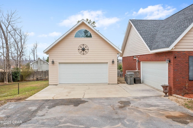 view of front of house featuring a shingled roof, brick siding, fence, and a garage