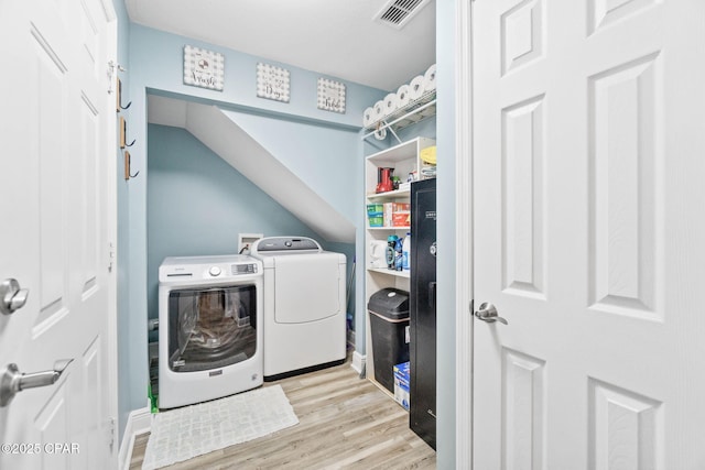 clothes washing area featuring laundry area, light wood-style flooring, washer and clothes dryer, and visible vents