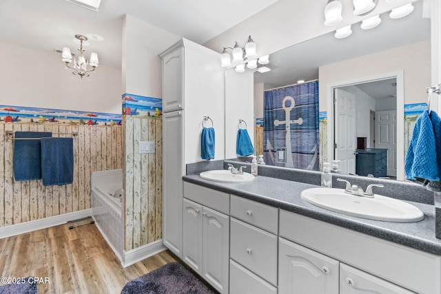 bathroom featuring wood finished floors, a garden tub, a sink, and double vanity