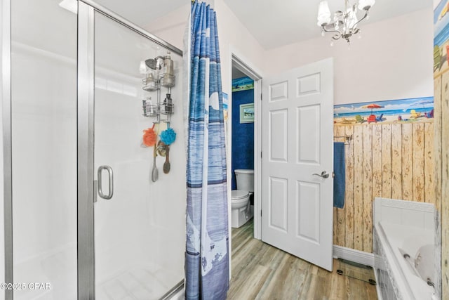 full bathroom with a chandelier, toilet, wood finished floors, a stall shower, and wallpapered walls