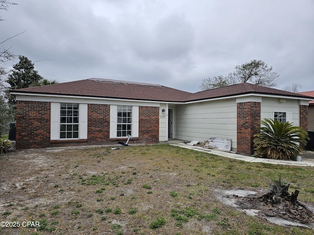 ranch-style home featuring brick siding and a front lawn