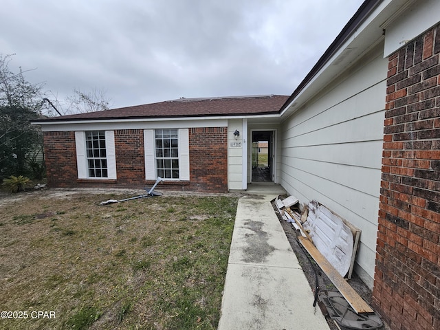 property entrance with brick siding and a lawn