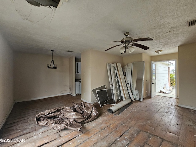 interior space featuring visible vents, ceiling fan, a textured ceiling, and baseboards