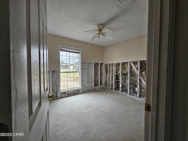 spare room featuring a ceiling fan, visible vents, and a textured ceiling