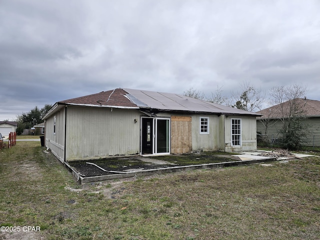 rear view of property with solar panels and a yard