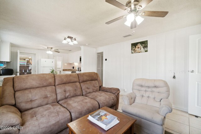 living area featuring light tile patterned floors, visible vents, and ceiling fan