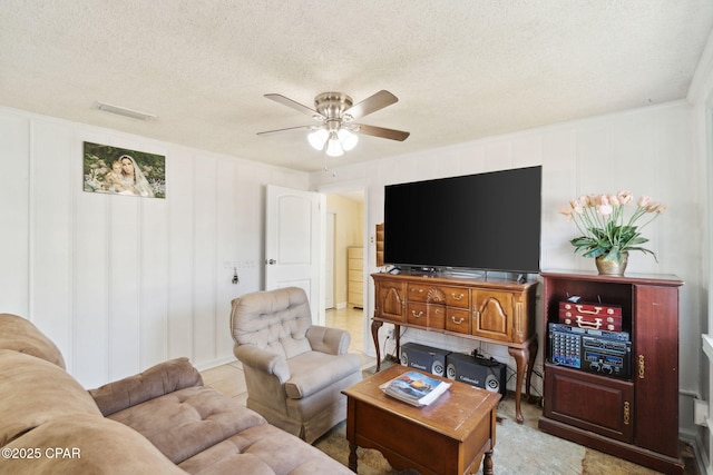 tiled living room featuring visible vents, a textured ceiling, and a ceiling fan