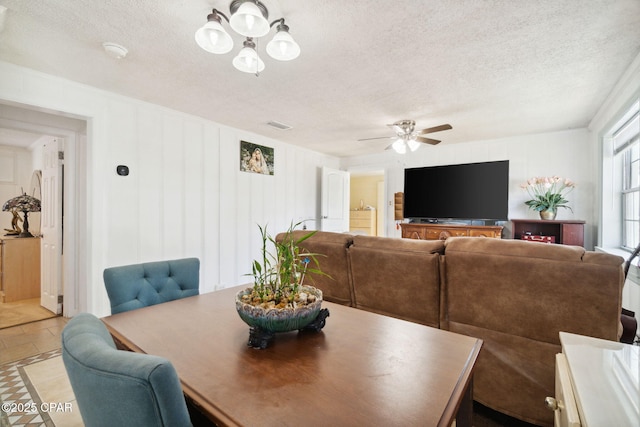 dining space featuring visible vents, ceiling fan with notable chandelier, and a textured ceiling