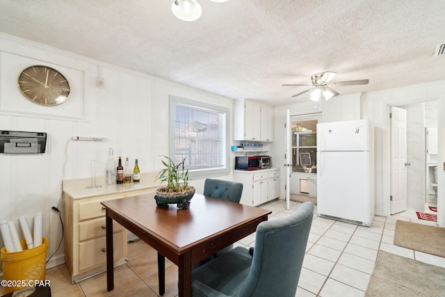 dining room featuring light tile patterned floors, visible vents, a textured ceiling, and a ceiling fan