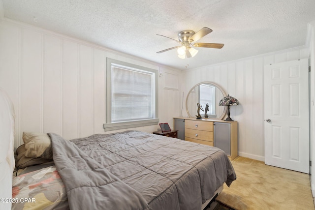 bedroom featuring light colored carpet, crown molding, a ceiling fan, and a textured ceiling