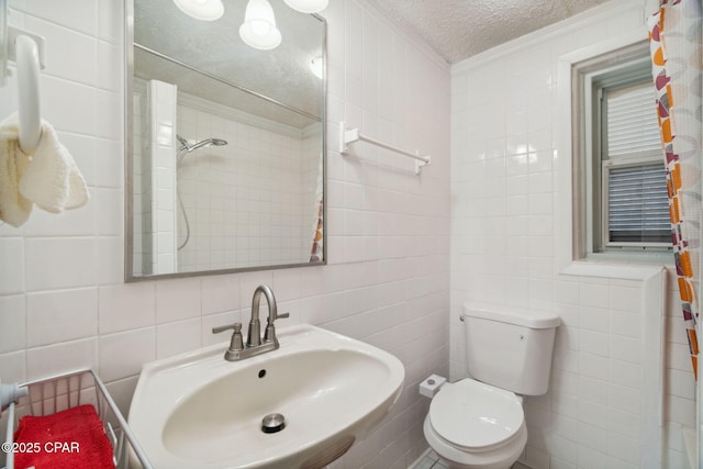 full bath featuring tile walls, toilet, ornamental molding, a textured ceiling, and a sink