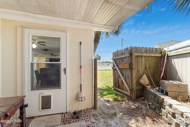 view of exterior entry with concrete block siding and fence