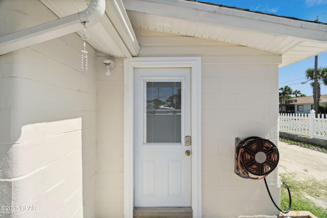 entrance to property with concrete block siding and fence