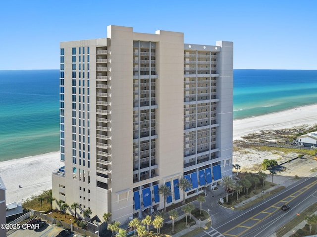 view of building exterior with a water view and a beach view