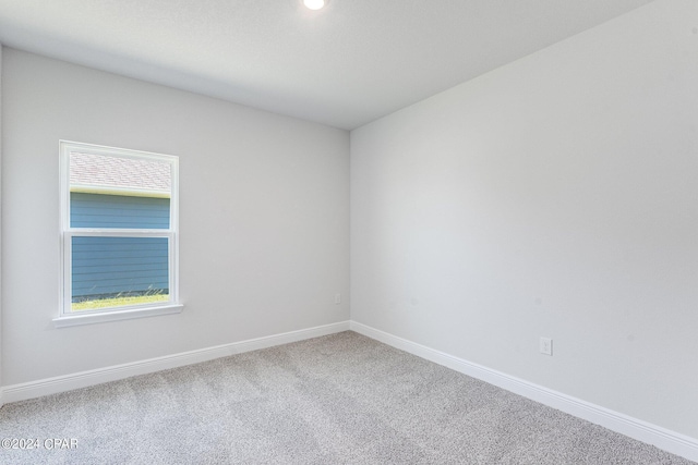 carpeted spare room featuring a healthy amount of sunlight and baseboards