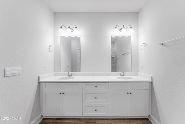 bathroom with double vanity, wood finished floors, a sink, and baseboards