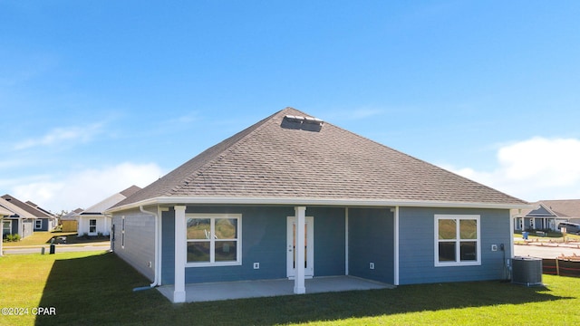 rear view of house with central AC, a shingled roof, a yard, a residential view, and a patio area