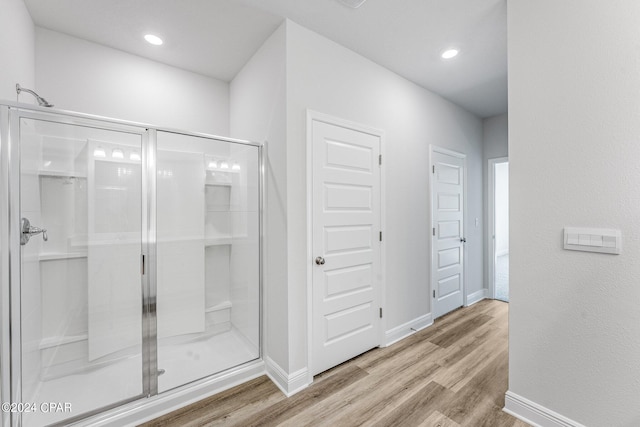 full bath with a stall shower, recessed lighting, wood finished floors, and baseboards