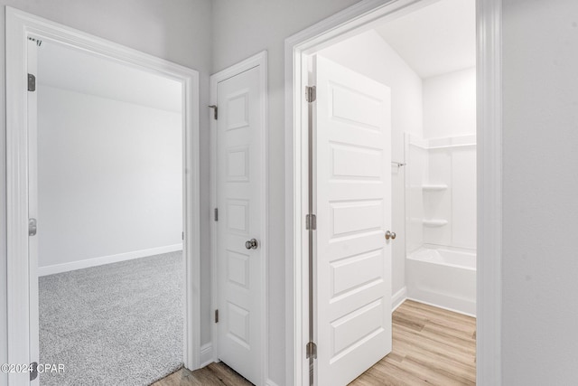 hallway with light wood-type flooring, light carpet, and baseboards