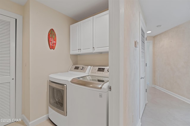 clothes washing area with washing machine and dryer, cabinet space, and baseboards