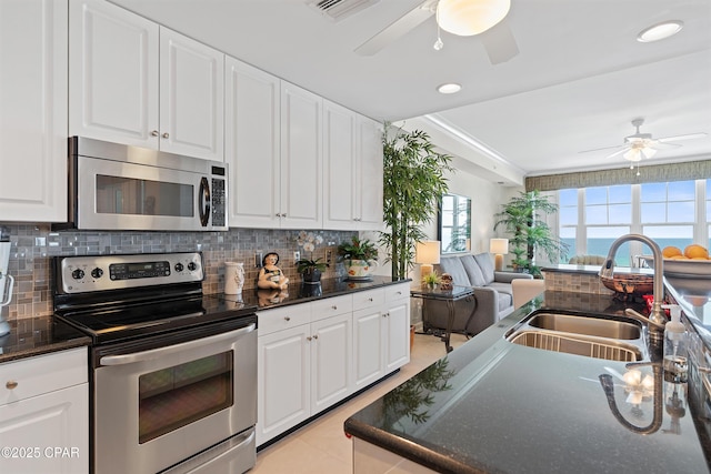 kitchen featuring visible vents, decorative backsplash, appliances with stainless steel finishes, open floor plan, and a sink