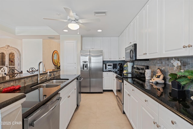 kitchen featuring light tile patterned floors, appliances with stainless steel finishes, ornamental molding, white cabinets, and a sink