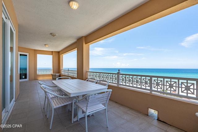 balcony featuring a water view and outdoor dining area