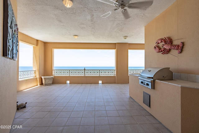 interior space featuring ceiling fan, exterior kitchen, area for grilling, and a water view