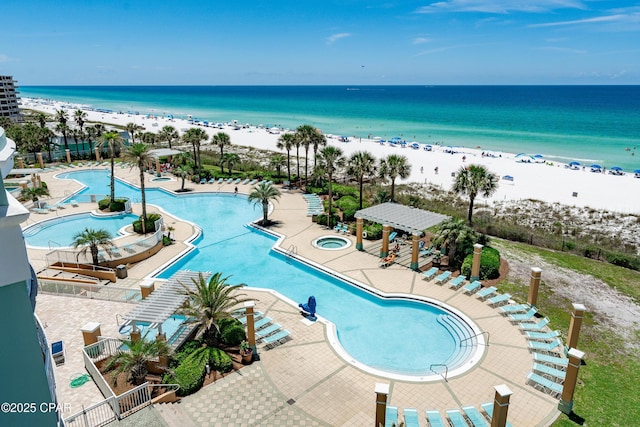 community pool featuring a patio area, a water view, and a beach view