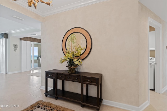 hall featuring light tile patterned flooring, a notable chandelier, baseboards, washer / clothes dryer, and crown molding